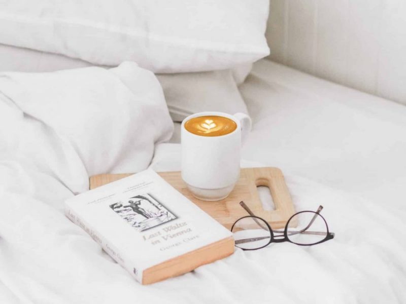 coffee, book and glasses on bed